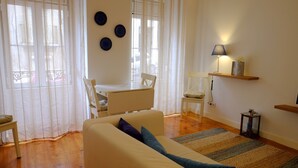 A living room with a sofa, a small table, a lamp, and a rug. - Travessa House I - Graça. Lisbon Historic Center (Lisbon)