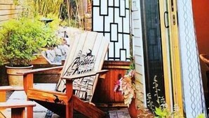 A patio with a wooden chair and table, potted plants, and a decorative wall. - PDX Eco Cottage Guesthouse (Portland)