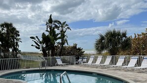 A pool area with lounge chairs and a view of the ocean. - Special Nov 14-21, 2026 - IRB Direct Beach Front Corner Condo (Indian Rocks Beach)
