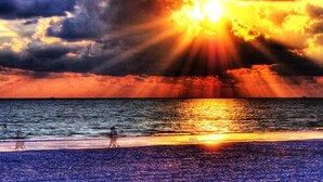 A sunset over the ocean with a beach in the foreground. - Special Nov 14-21, 2026 - IRB Direct Beach Front Corner Condo (Indian Rocks Beach)