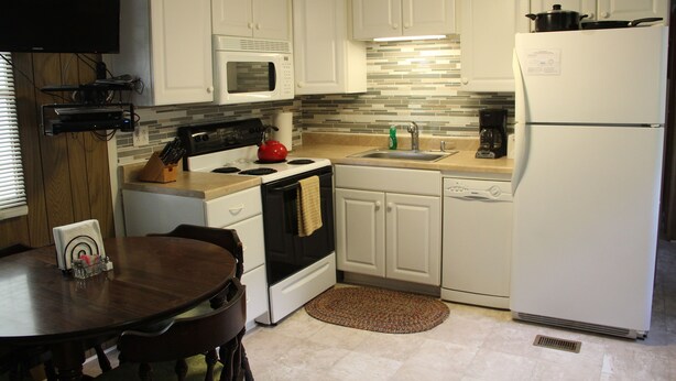 A modern kitchen with white cabinets, a microwave, stove, sink, and a refrigerator. - Walk to White Oak Canyon Trail in Shenandoah National Park (Syria)