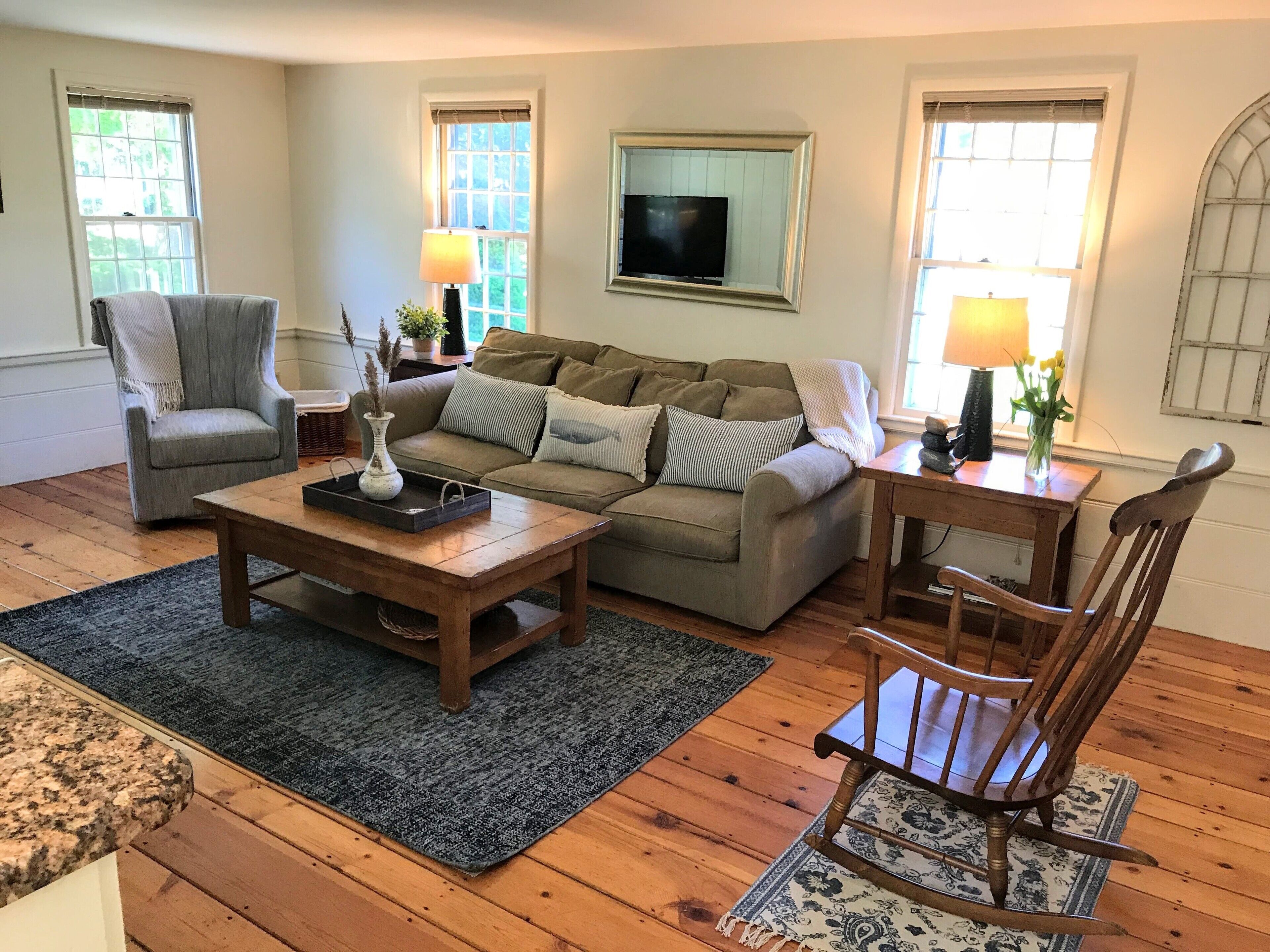 A living room with a sofa, armchair, coffee table, and wooden flooring.