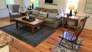 Un salon comprenant un canapé, un fauteuil, une table basse et un plancher en bois.