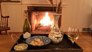 Un plateau avec une bouteille de vin, un bol de chips, un verre de vin et un vase contenant des plantes séchées.