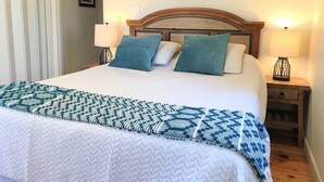 Un lit bien fait, avec une couverture à motifs, deux oreillers et un décor mural représentant un navire.