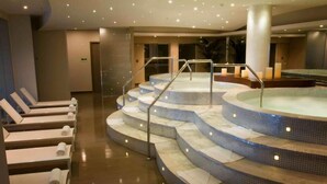 A spa area with a hot tub, seating area, and a staircase leading to a higher platform.