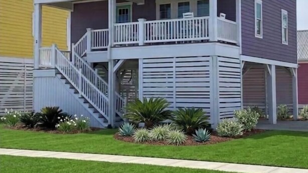 A two-story house with a balcony, a staircase, and a small garden.