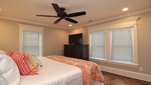 A bedroom with a bed, a ceiling fan, a dresser, and a TV. - Luxury New Home: Ocean and City Light View Home + Steps to Restaurants sleeps 6 (Carolina Beach)