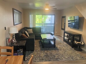 A living room with a sofa, coffee table, TV, and a view of the outdoors. - Tempe Arizona State University ASU 960 Sq Ft Executive Condo  (Tempe)