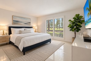 A modern bedroom with a bed, bedside tables, a desk, a potted plant, and a painting on the wall.