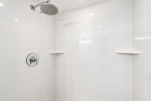 A modern shower with a handheld showerhead and a wall-mounted control valve.