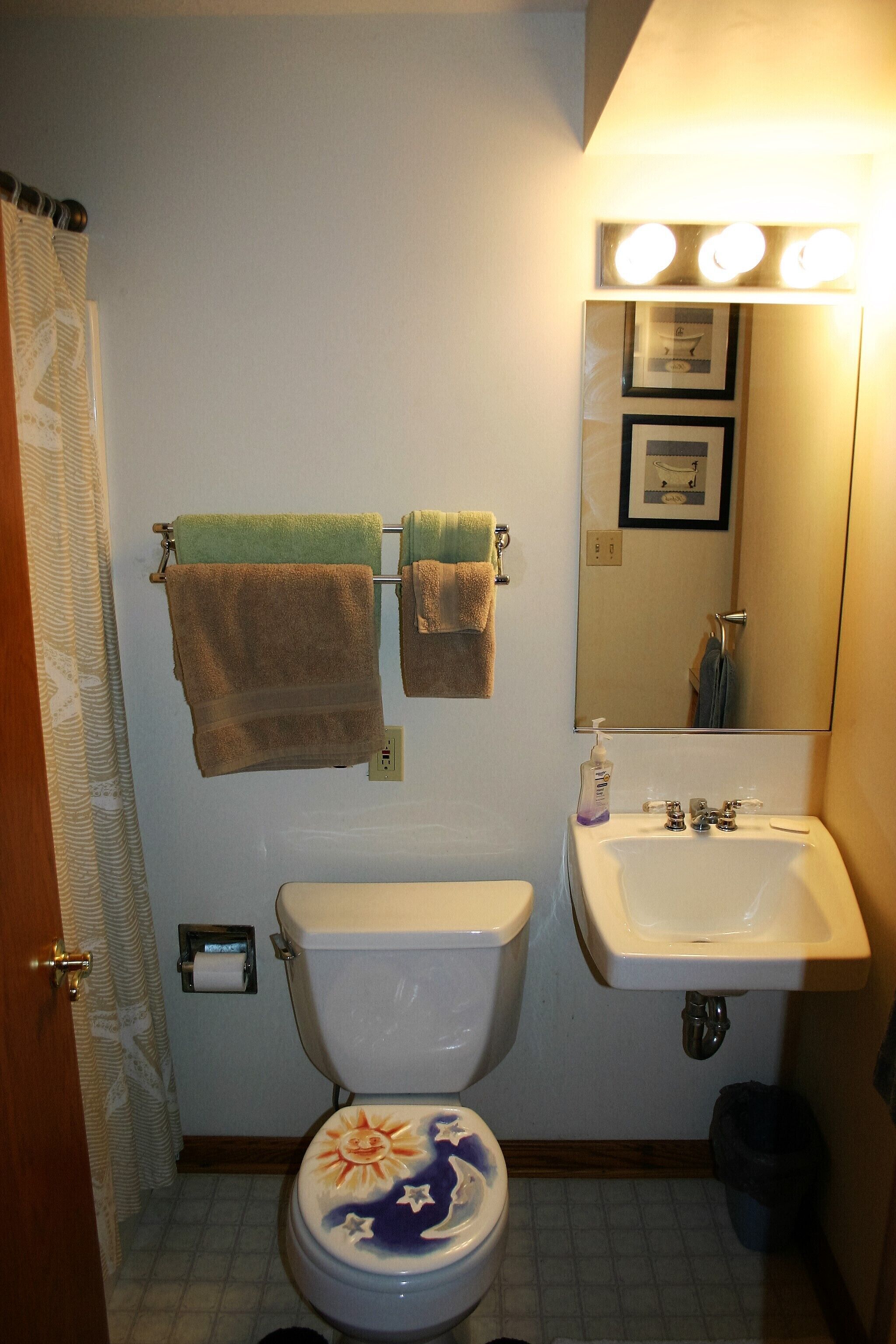 A bathroom with a toilet, sink, and two towels hanging on a rack.