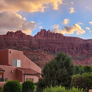 A building with a flat roof and a window, surrounded by greenery, with a mountain in the background. - Southwest Charm and Amazing Views, just minutes from town! (Moab)