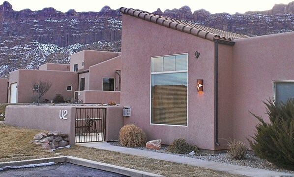 A modern building with a pink facade, a gated entrance, and a view of a mountainous landscape. - Southwest Charm and Amazing Views, just minutes from town! (Moab)