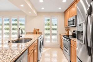 A modern kitchen with granite countertops, stainless steel appliances, and wooden cabinets.