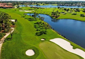Un parcours de golf avec des bunkers de sable, des obstacles d’eau et un étang.