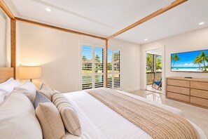 A bedroom with a bed, a TV, a balcony with a view, and a wooden ceiling.