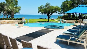 Zona de piscina con sillones de descanso, una bañera de hidromasaje y vista al mar.
