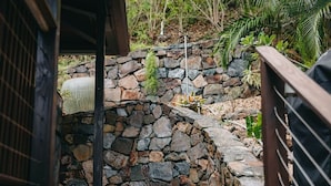 Un muro de piedra con barandilla de metal, un sendero de piedra y algo de vegetación.