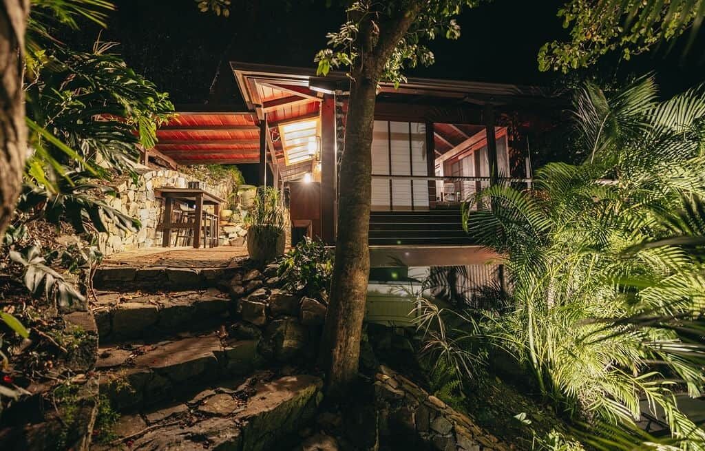 A traditional Japanese-style building with a stone pathway leading to the entrance, surrounded by lush greenery.