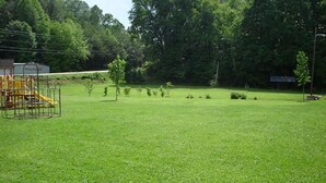 A grassy field with a playground structure and trees in the background. - Apartment in town (Franklin)