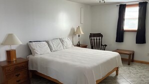 A bedroom with a bed, two bedside tables, a nightstand, a chair, a bench, a window with curtains, and a ceiling fan. - Apartment in town (Franklin)