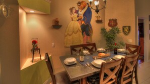 Comedor con un mural grande en la pared, una araña y una mesa de comedor dispuesta para cuatro.