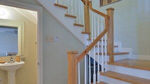 Un escalier avec des marches en bois et des balustrades blanches, menant à l’étage supérieur.