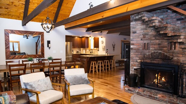 A spacious living room with wooden floors, a fireplace, and a dining area with wooden furniture.