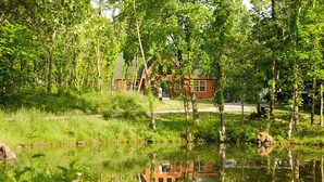 Une cabane entourée d’une forêt dense et située près d’un étang.