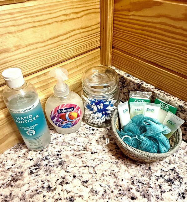 A bathroom counter with hand sanitizer, soap, cotton swabs, and eco-friendly products.