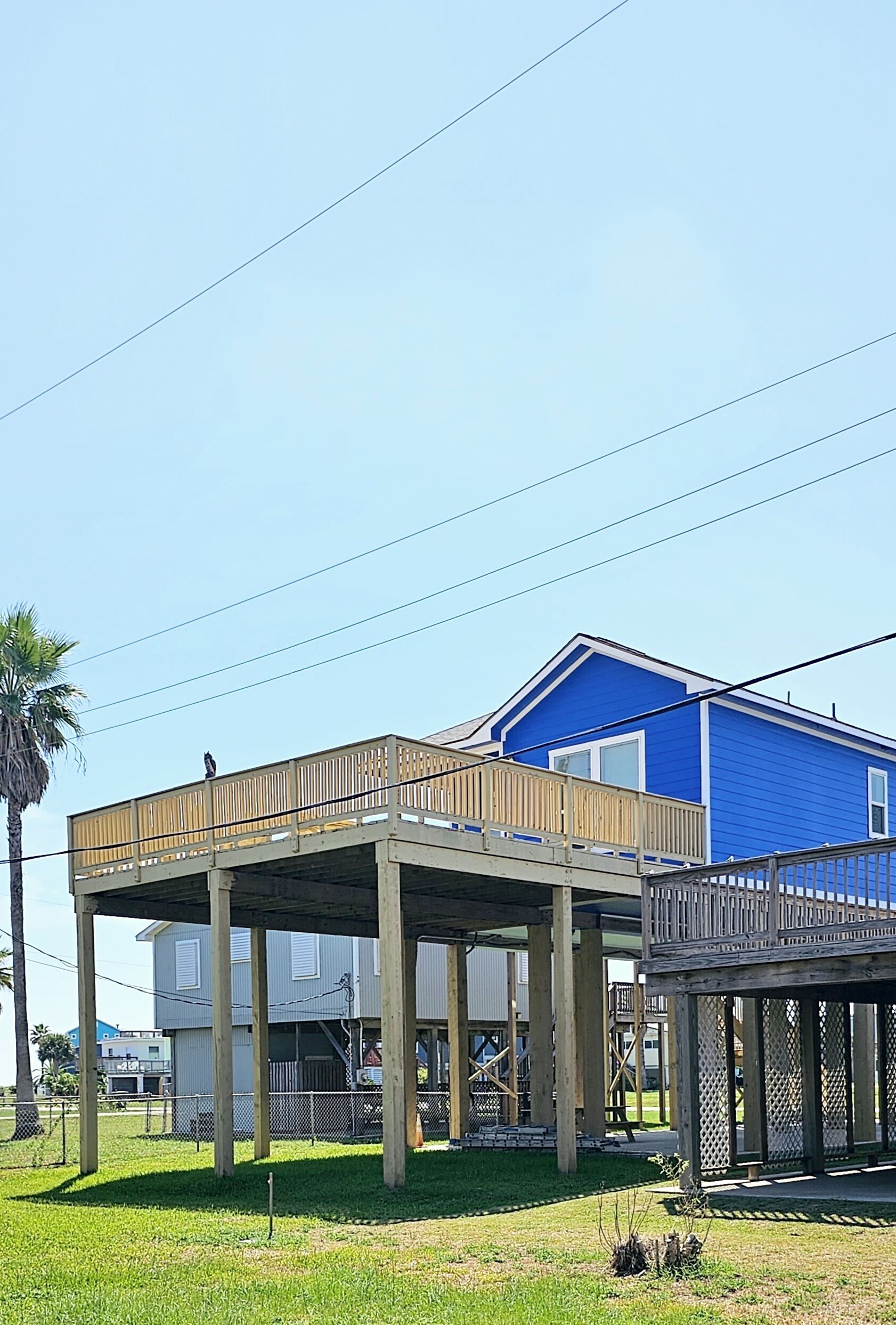 Un edificio de dos pisos con una terraza de madera y fachada azul.