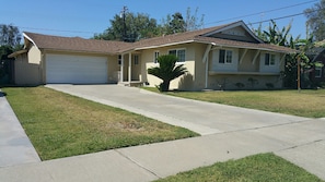 A single-story house with a garage, a front lawn, and a palm tree.