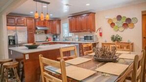 A modern kitchen with wooden cabinets, a central island, and pendant lighting. - Cozy Vacation home-3 bedrooms/2 bath- 1 mile to Disney Parking Tram (Anaheim)
