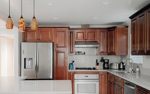 Una cocina moderna con armarios de madera, electrodomésticos de acero inoxidable e iluminación colgante.