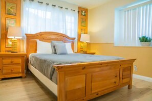 Un dormitorio con una cama de madera, dos mesitas de noche con lámparas, una ventana con persianas y un reloj de pared.
