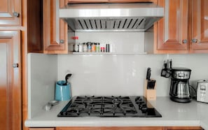 A kitchen with a gas stove, a coffee maker, and various kitchen utensils.