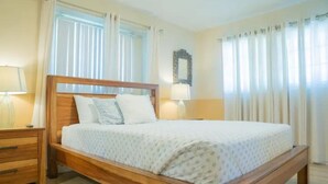 A bedroom with a wooden bed, two bedside tables, and a mirror on the wall. - Cozy Vacation home-3 bedrooms/2 bath- 1 mile to Disney Parking Tram (Anaheim)