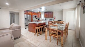 Una cocina moderna con una isla central, mesa de comedor de madera y taburetes de bar.