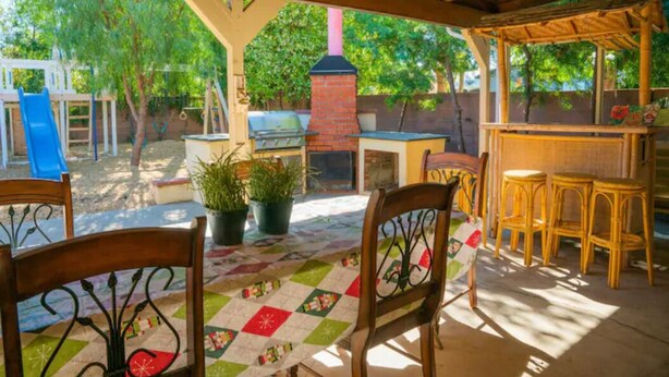 An outdoor patio with a grill, a play area, and a seating area with chairs and a table. - Cozy Vacation home-3 bedrooms/2 bath- 1 mile to Disney Parking Tram (Anaheim)