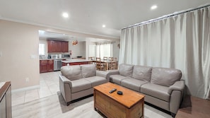 A living room with a sofa, a coffee table, and a kitchen in the background.