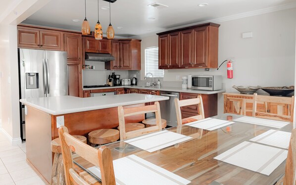 A modern kitchen with wooden cabinets, stainless steel appliances, and a central island with seating.