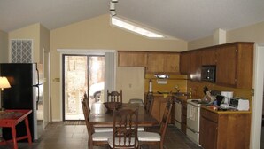 Une cuisine spacieuse avec un coin repas, comprenant un grand îlot central, des meubles en bois et un four à micro-ondes encastré.
