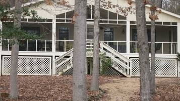 A cabin with a covered porch, white railings, and a staircase leading to the entrance.