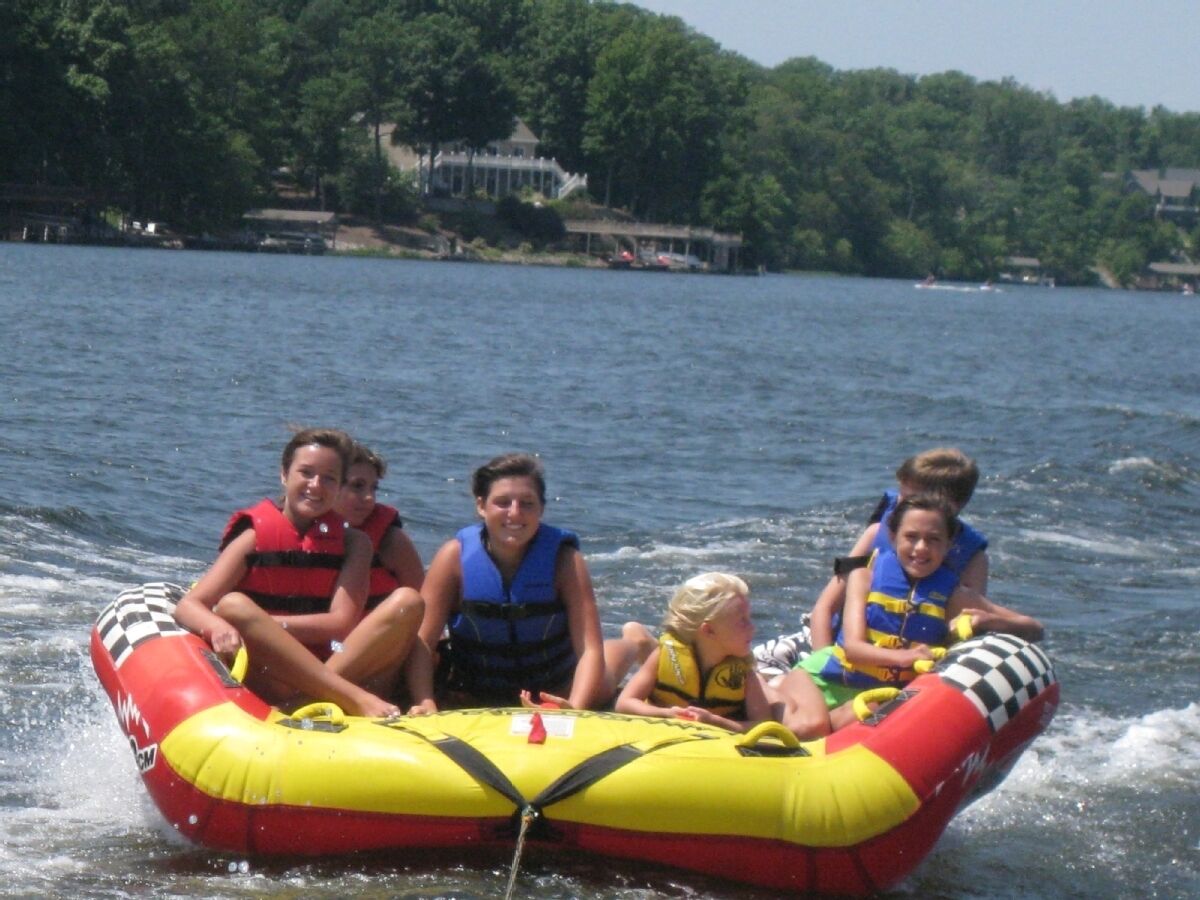 Un grupo de personas en un bote inflable amarillo y rojo sobre un lago.
