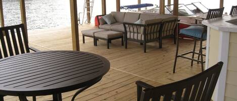 Une terrasse extérieure couverte, avec une table ronde et des chaises, un canapé et un coin bar.