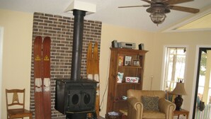 Un salon avec une cheminée en briques, un canapé, un fauteuil en bois et un ventilateur de plafond.