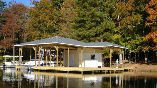 Une maison située au bord de l’eau, dotée d’une terrasse couverte, de bateaux amarrés et offrant un cadre paisible au bord d’un lac.