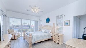 Un dormitorio amplio con una cama grande, una zona de estar con una silla, un tocador y vistas al exterior.