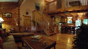 L’intérieur chaleureux d’un chalet en bois comprend un escalier en bois, un coin repas et un salon aménagé avec un canapé et une table basse.